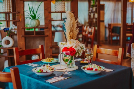 Cină aranjată cu salate, vin și decorațiuni colorate în interiorul primitor al restaurantului Dukov House, orașul Kavarna